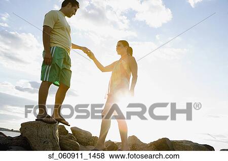 Hispanic couple holding hands on rocks at beach View Large Photo Image Stock Photo - Hispanic couple holding hands on rocks at beach. Fotosearch