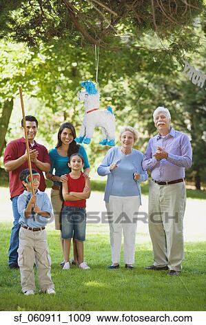 Stock Photo - Hispanic family watching boy hit pinata. Fotosearch