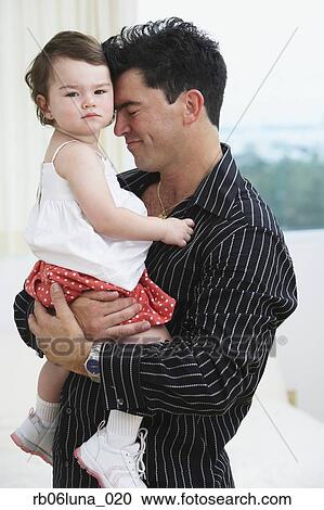 Stock Image - Hispanic father hugging young daughter. Fotosearch