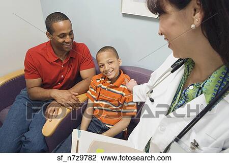 Hispanic female doctor smiling at African father and son in waiting room View Large Photo Image Stock Image - Hispanic female doctor smiling at African father and son in waiting room. Fotosearch