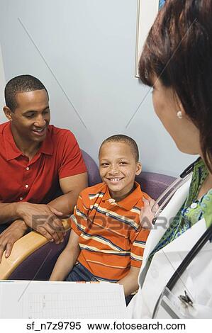 Hispanic female doctor talking to African father and son in waiting room View Large Photo Image Stock Photography - Hispanic female doctor talking to African father and son in waiting room. Fotosearch