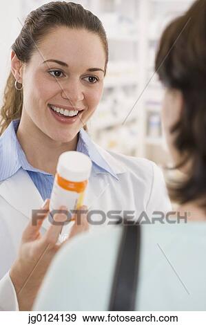 Hispanic female pharmacist giving medication to customer View Large Photo Image Stock Photo - Hispanic female pharmacist giving medication to customer. Fotosearch