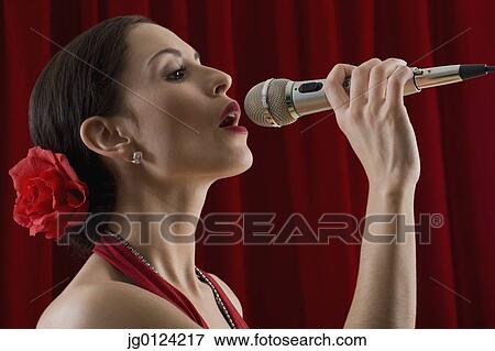 Hispanic female singing into microphone View Large Photo Image Stock Photo - Hispanic female singing into microphone. Fotosearch
