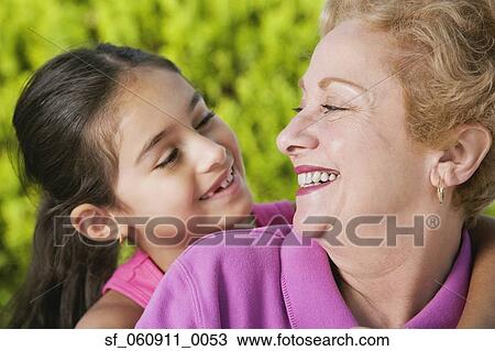 Stock Image - Hispanic grandmother and granddaughter smiling at each other. Fotosearch