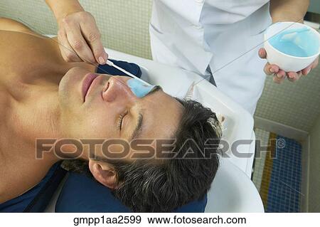 Stock Photo - Hispanic man receiving spa facial treatment. Fotosearch
