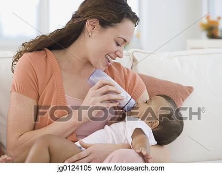 Hispanic mother bottle feeding baby View Large Photo Image Stock Photography - Hispanic mother bottle feeding baby. Fotosearch