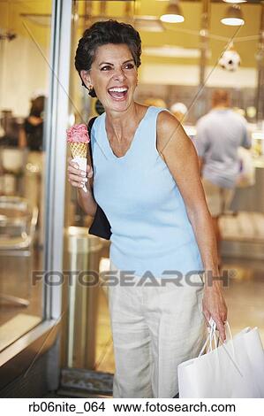 Hispanic woman eating ice cream cone in front of shop View Large Photo Image Picture - Hispanic woman eating ice cream cone in front of shop. Fotosearch