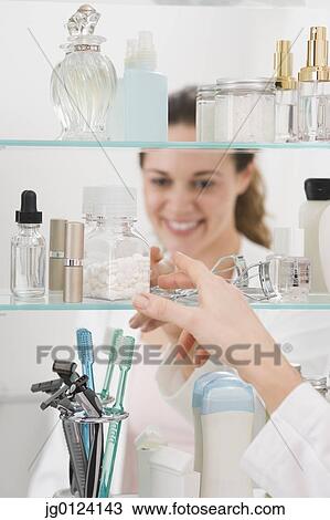 Hispanic woman reaching into medicine cabinet View Large Photo Image Stock Image - Hispanic woman reaching into medicine cabinet. Fotosearch