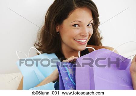 Stock Image - Hispanic woman smiling with shopping bags. Fotosearch
