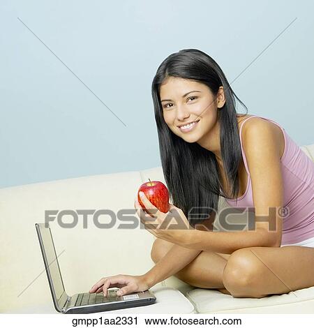 Hispanic woman using laptop and eating apple View Large Photo Image Stock Image - Hispanic woman using laptop and eating apple. Fotosearch
