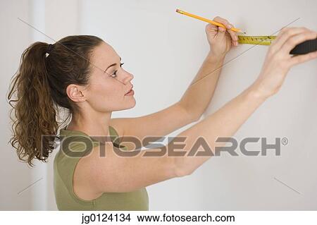 Hispanic woman using tape measure on wall View Large Photo Image Picture - Hispanic woman using tape measure on wall. Fotosearch