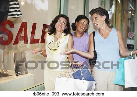 Hispanic women shrugging shoulders next to shop with sale sign View Large Photo Image Stock Image - Hispanic women shrugging shoulders next to shop with sale sign. Fotosearch