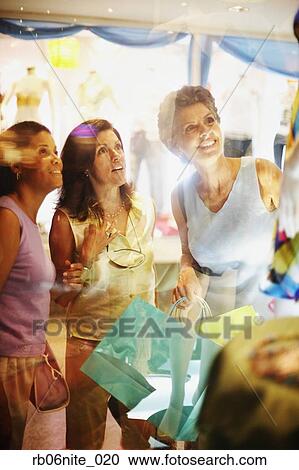 Stock Image - Hispanic women with shopping bags window shopping. Fotosearch