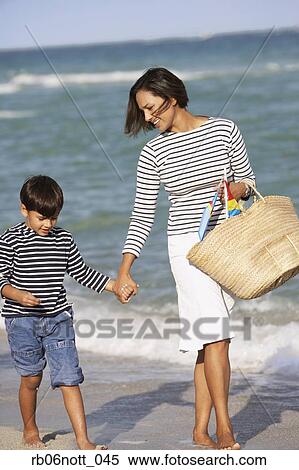Stock Photography - Indian mother and son holding hands and walking on beach. Fotosearch