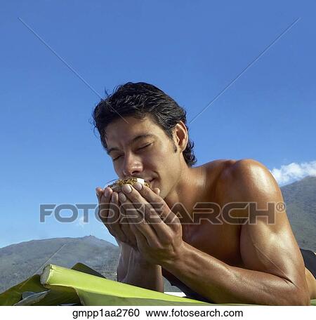 Low angle view of Asian man laying on banana leaves and smelling bowl of botanical medicine View Large Photo Image Stock Image - Low angle view of Asian man laying on banana leaves and smelling bowl of botanical medicine. Fotosearch