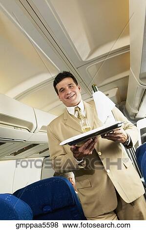 Low angle view of Hispanic male flight attendant carrying wine on a tray View Large Photo Image Stock Photo - Low angle view of Hispanic male flight attendant carrying wine on a tray. Fotosearch
