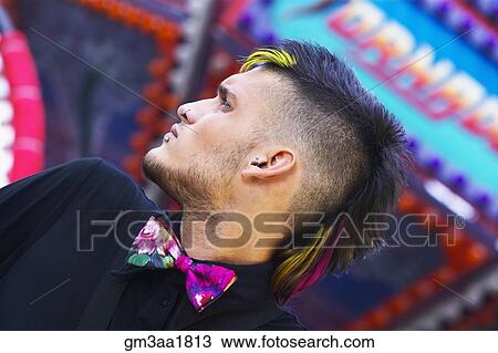 Stock Image - Low angle view of young Hispanic male punk with mohawk and bowtie. Fotosearch