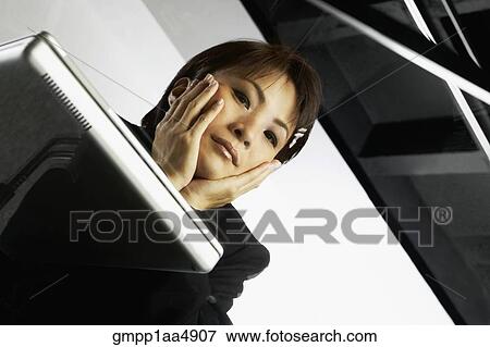 Low angle view through glass desk of Asian businesswoman and laptop View Large Photo Image Stock Photo - Low angle view through glass desk of Asian businesswoman and laptop. Fotosearch