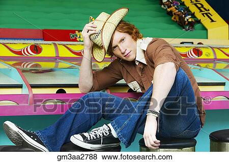 Male teenager with straw hat sitting on stool at carnival booth View Large Photo Image Stock Photo - Male teenager with straw hat sitting on stool at carnival booth. Fotosearch