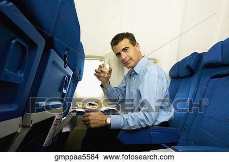 Man eating and toasting with wine on airplane View Large Photo Image Picture - Man eating and toasting with wine on airplane. Fotosearch