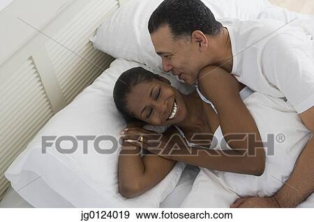 Stock Photo - Middle-aged African couple hugging in bed. Fotosearch