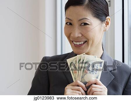 Middle-aged Asian businesswoman holding yen banknotes View Large Photo Image Stock Image - Middle-aged Asian businesswoman holding yen banknotes. Fotosearch