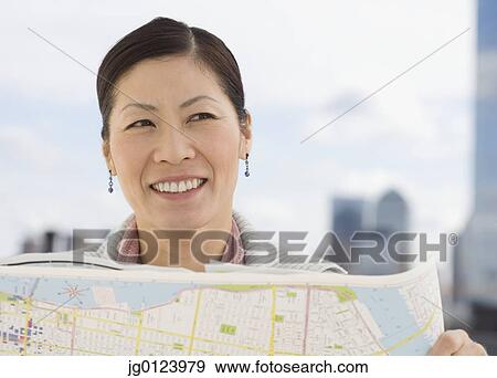Stock Photo - Middle-aged Asian woman holding map . Fotosearch