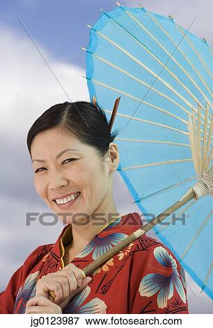 Stock Photo - Middle-aged Asian woman in traditional dress with parasol. Fotosearch
