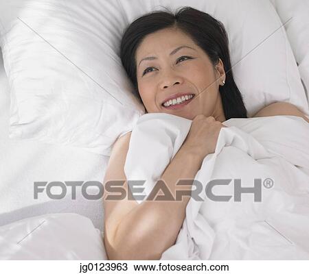 Middle-aged Asian woman laying in bed View Large Photo Image Stock Image - Middle-aged Asian woman laying in bed. Fotosearch