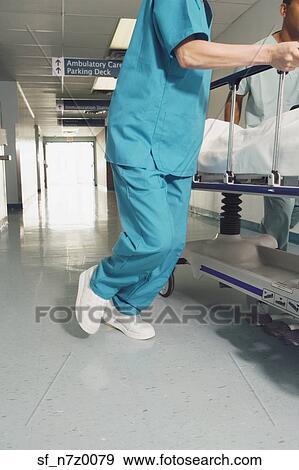 Nurse wheeling gurney in corridor of hospital View Large Photo Image Stock Photo - Nurse wheeling gurney in corridor of hospital. Fotosearch
