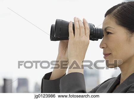 Stock Photograph - Profile of Asian businesswoman looking through binoculars. Fotosearch