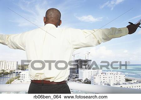 Rear view of African businessman on balcony View Large Photo Image Picture - Rear view of African businessman on balcony. Fotosearch
