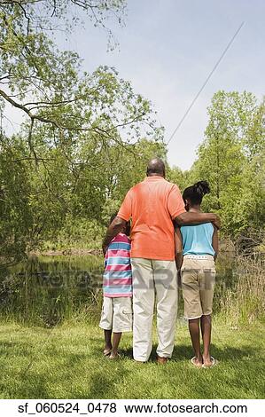 Rear view of African grandfather and grandchildren hugging in park View Large Photo Image Stock Photo - Rear view of African grandfather and grandchildren hugging in park. Fotosearch