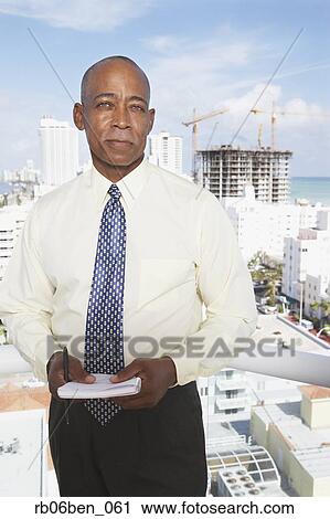 Stock Image - Senior African businessman on balcony. Fotosearch