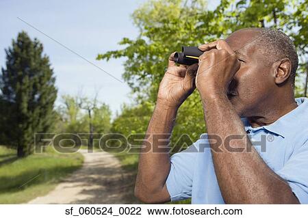 Senior African man using binoculars in park View Large Photo Image Stock Image - Senior African man using binoculars in park. Fotosearch