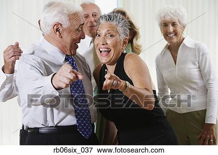 Stock Photo - Senior couple at party pointing in surprise. Fotosearch