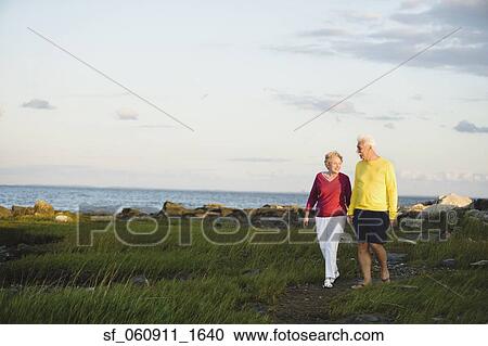 Stock Image - Senior couple walking near ocean. Fotosearch