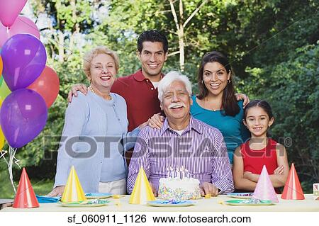 Stock Photograph - Senior Hispanic man with family and birthday cake. Fotosearch
