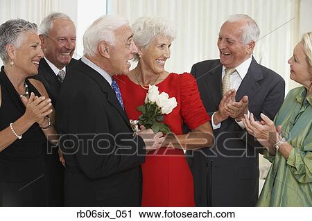 Senior man giving wife bouquet of flowers while friends clap View Large Photo Image Stock Image - Senior man giving wife bouquet of flowers while friends clap. Fotosearch