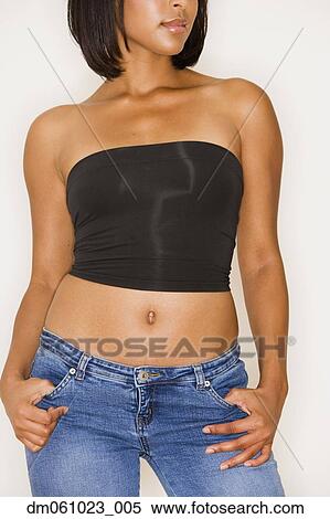 Stock Photography - Studio shot of young Hispanic woman in strapless top and jeans. Fotosearch