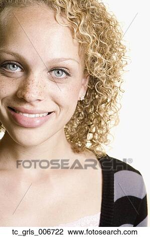 Stock Image - Studio shot of young woman with freckles smiling. Fotosearch