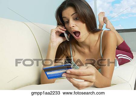 Surprised Hispanic woman laying on sofa with cell phone and credit card View Large Photo Image Stock Image - Surprised Hispanic woman laying on sofa with cell phone and credit card. Fotosearch