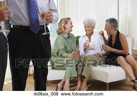Stock Photo - Three senior women talking on sofa at party. Fotosearch