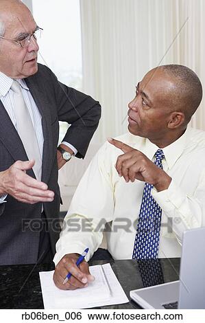 Stock Photograph - Two senior businessmen talking in office. Fotosearch
