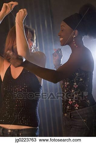 Stock Image - Two women dancing in nightclub. Fotosearch