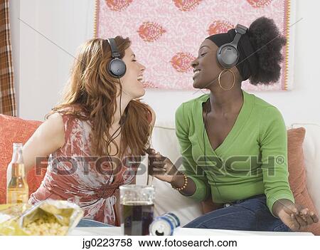 Stock Photo - Two women singing to headphones. Fotosearch