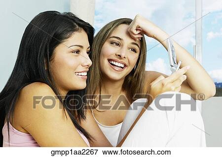 Two young Hispanic women looking at cell phone View Large Photo Image Stock Photo - Two young Hispanic women looking at cell phone. Fotosearch
