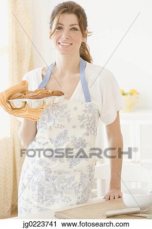 Woman in apron holding tray of cupcakes View Large Photo Image Stock Image - Woman in apron holding tray of cupcakes. Fotosearch
