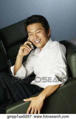 Young Asian businessman using cell phone in armchair View Large Photo Image Stock Photo - Young Asian businessman using cell phone in armchair. Fotosearch