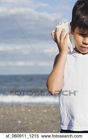 Young Hispanic boy listening to seashell View Large Photo Image Stock Photography - Young Hispanic boy listening to seashell. Fotosearch